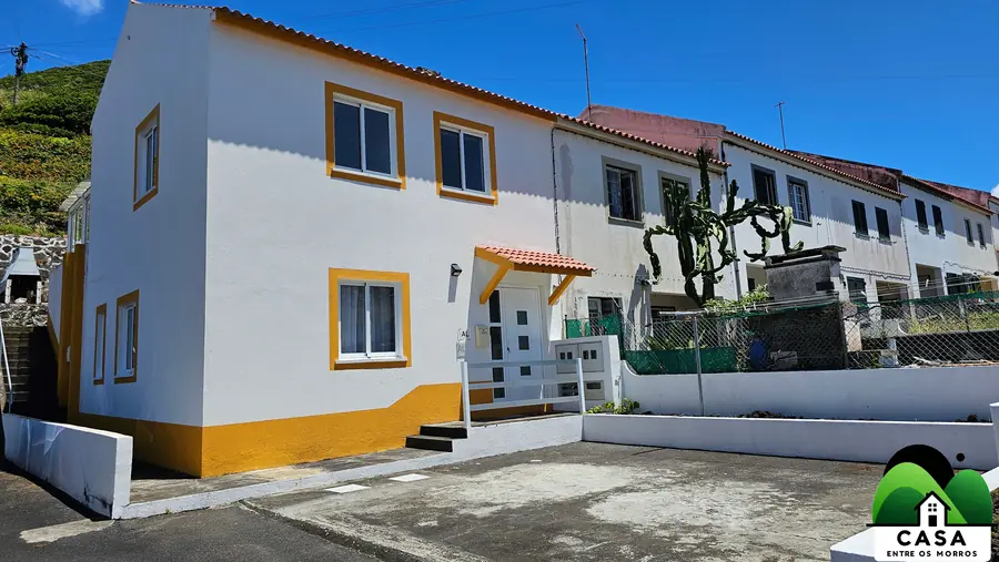 Rua e fachada da casa sob céu azul