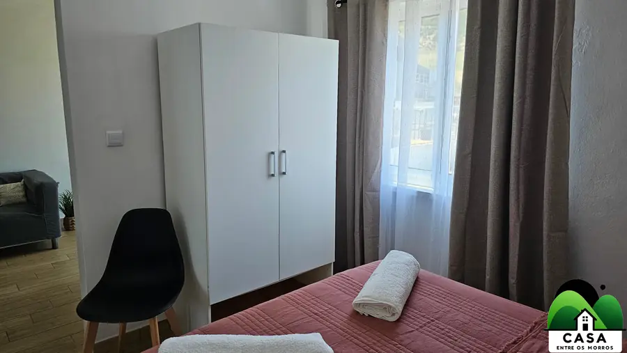 Quarto de casal com roupa de cama rosada e toalhas dobradas